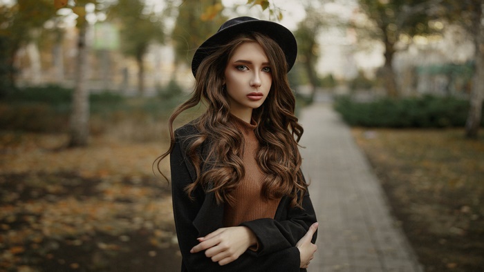 Woman wearing a hat and coat in a park