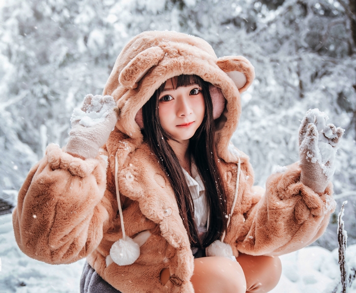 Woman in a bear hoodie in the snow