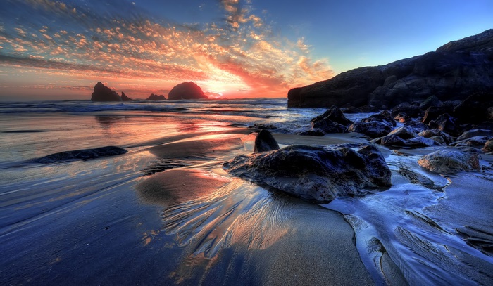 Beach with rocks and sunset over the ocean