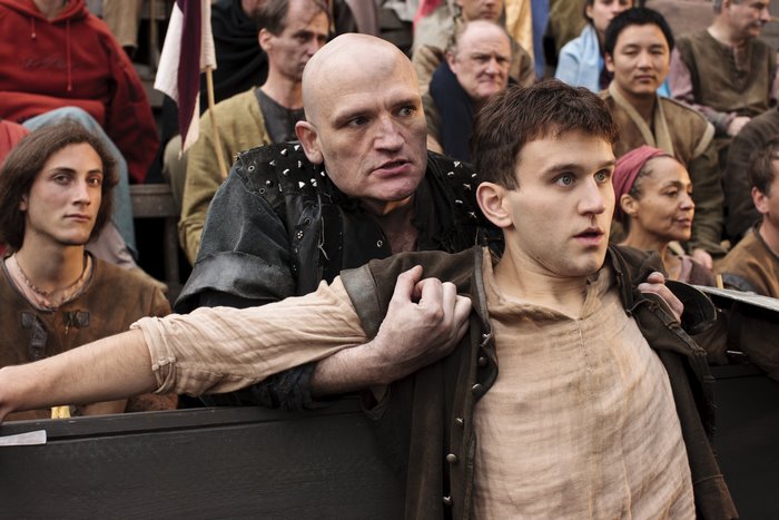 Two men in a crowd, one bald man grabbing another