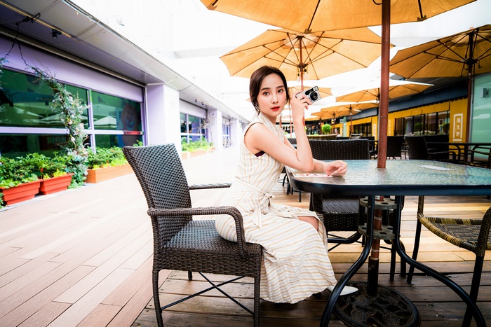 Asian woman with camera sitting at table