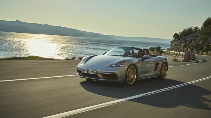 Silver Porsche Boxster driving on a coastal road