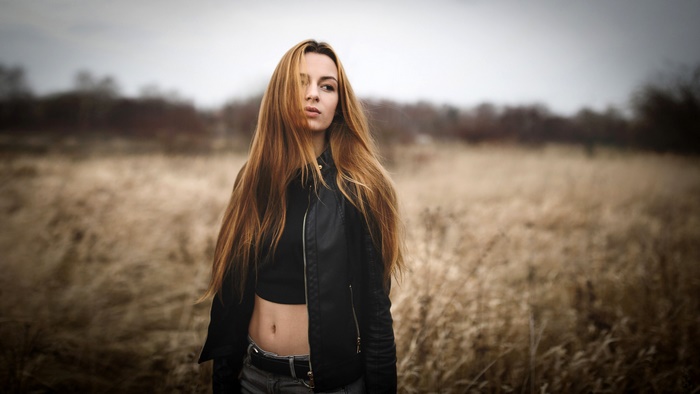 Woman with long hair in a leather jacket in a field