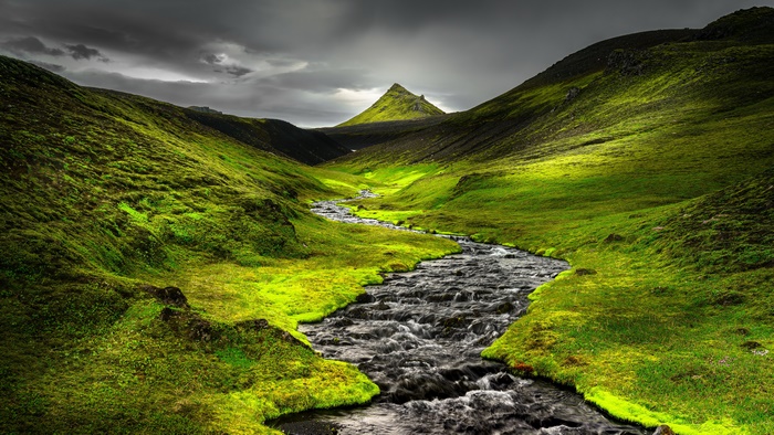 River landscape with green hills and a mountain