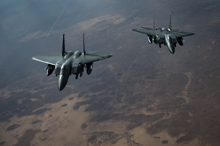 Two United States Air Force F-15E Strike Eagles flying over desert terrain