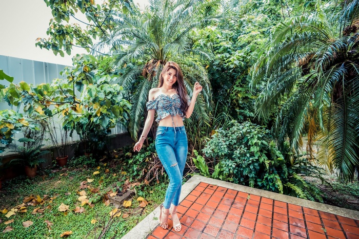 Asian woman with long brown hair in jeans and crop top