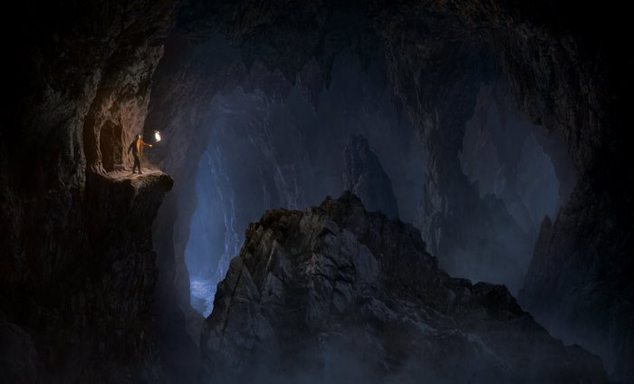 Man with lantern in dark cave