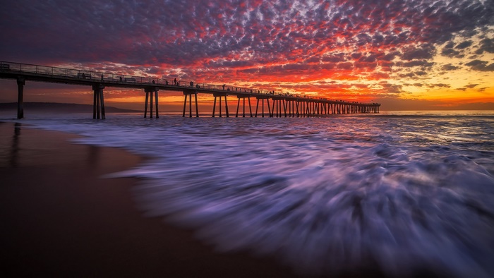 Pier over ocean at sunset with colorful clouds
