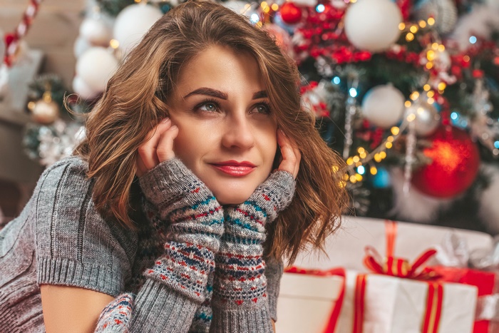 Woman in Christmas sweater with Christmas tree and gifts