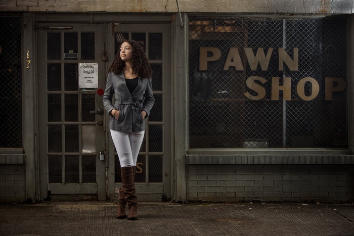 Woman in coat standing in front of pawn shop