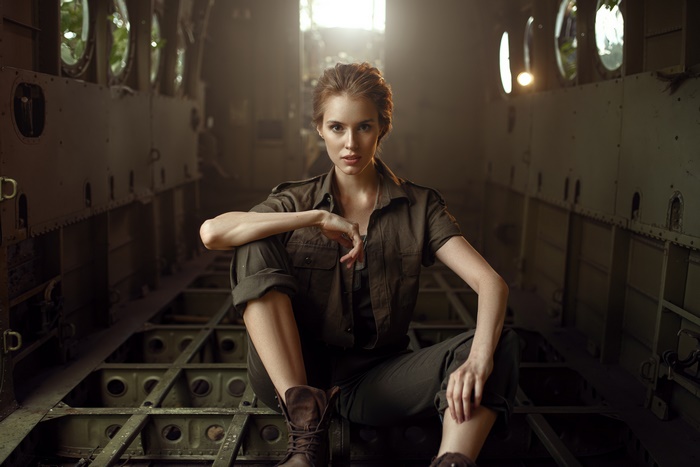 Woman in military-style clothing sitting inside an abandoned aircraft