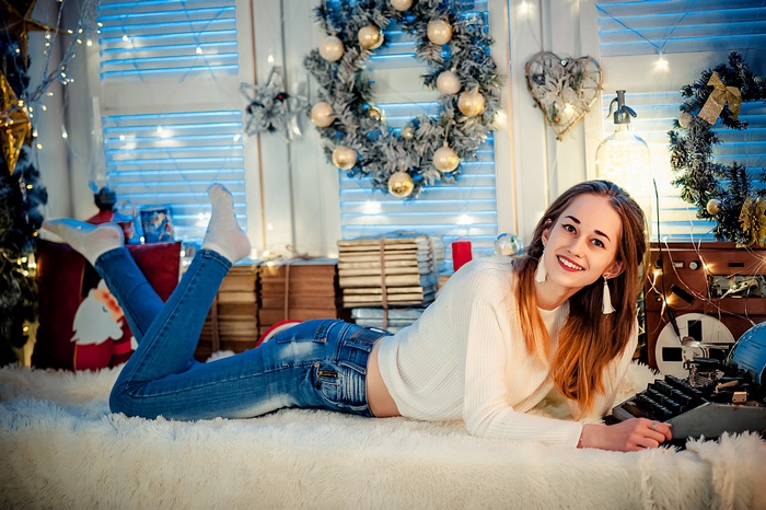 Woman in jeans and sweater lying down with Christmas decorations