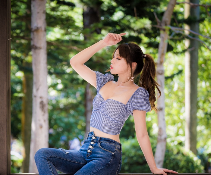 Woman with ponytail in blue gingham top and jeans