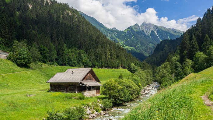 Wooden cabin by a stream in the Alps
