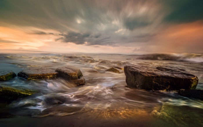 Ocean waves crashing on rocks at sunset
