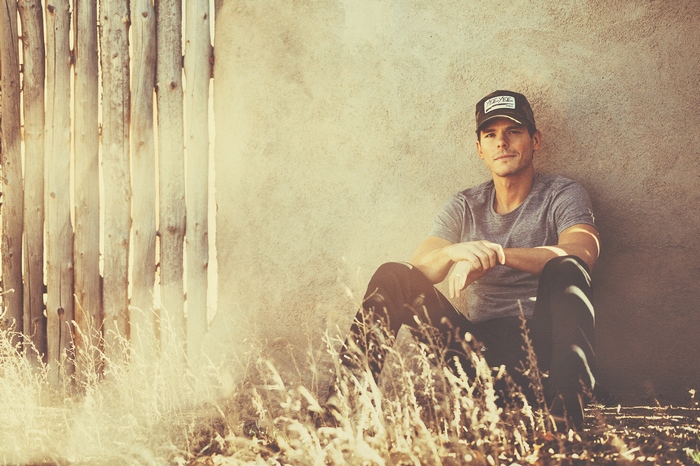 Granger Smith sitting by a fence and wall