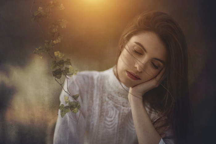 Woman with eyes closed resting her head on her hand