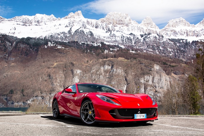 Red Ferrari 812 Superfast parked with snowy mountains