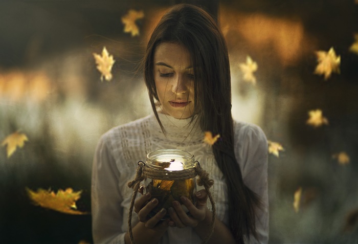 Woman holding a jar with leaves and light