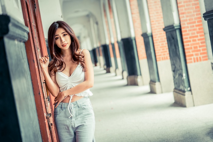 Asian woman with brunette hair posing in a hallway