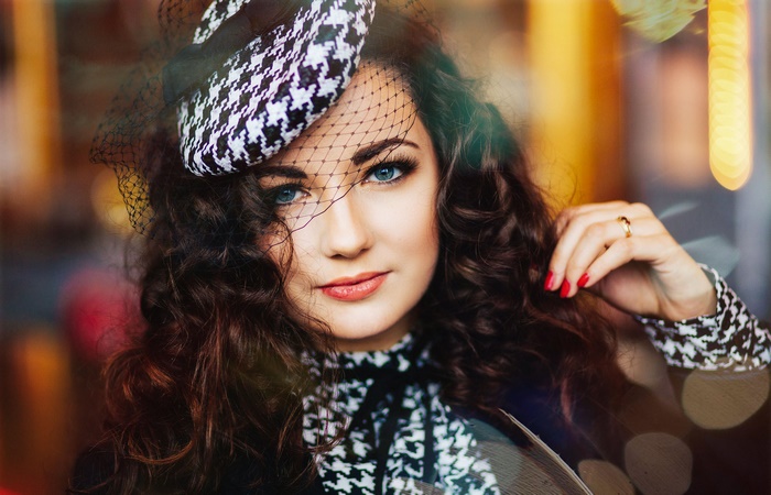 Woman with blue eyes and curly hair wearing a hat