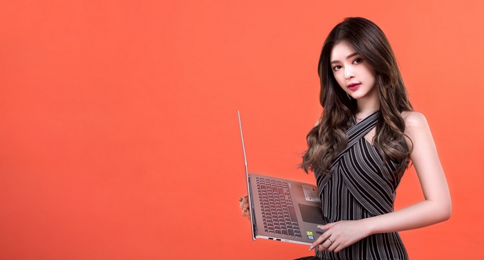 Asian woman with long brown hair holding a laptop