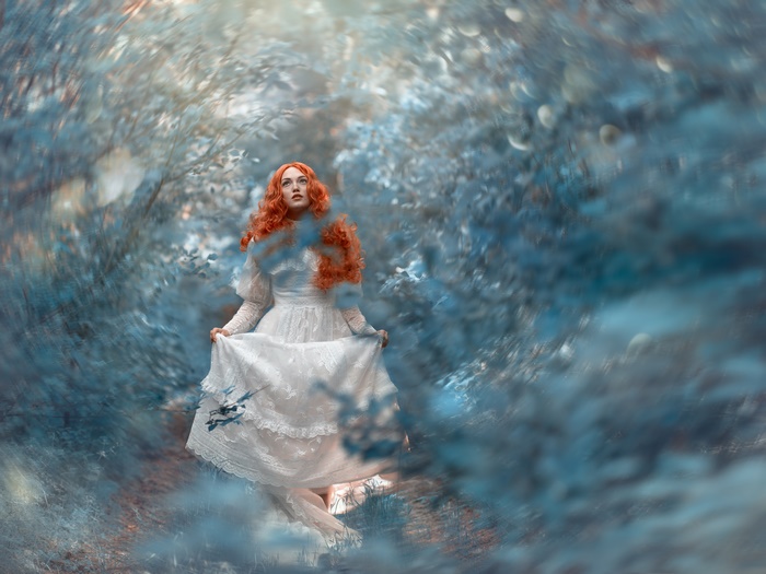 Redhead woman in white dress in forest