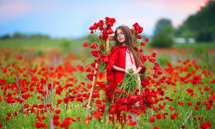 Girl in red cape in poppy field