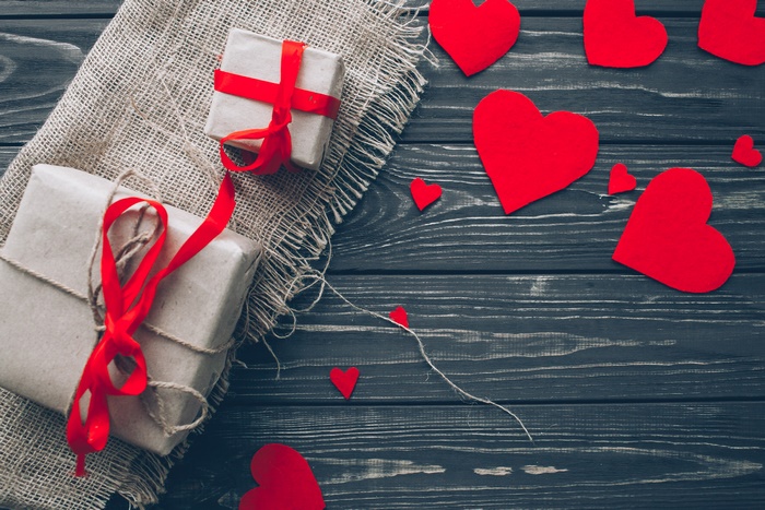 Gifts and red hearts on a wooden background