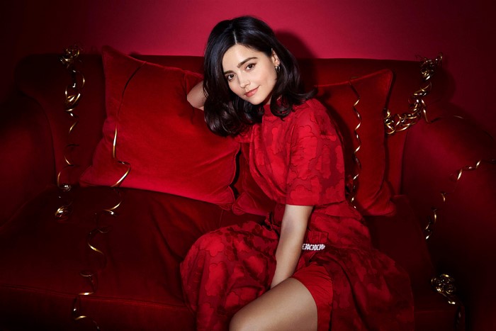 Jenna Coleman in a red dress on a red couch
