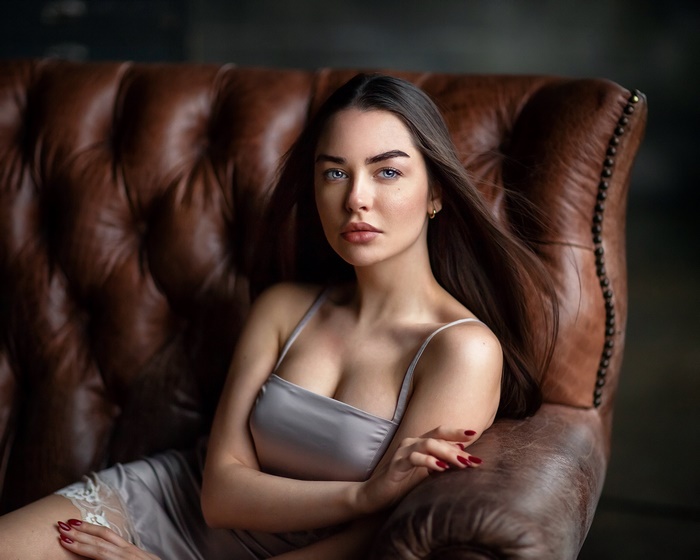 Woman with black hair and blue eyes sitting on a leather couch
