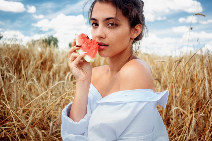 Woman eating watermelon in a wheat field