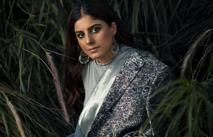 Isha Talwar in a patterned jacket surrounded by tall grass