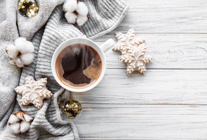Coffee cup with snowflake cookies and cotton on a sweater