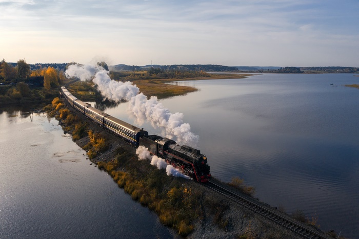 Steam Train Traveling Along a Lake in Autumn
