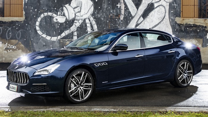 Blue Maserati Quattroporte GranLusso parked in front of graffiti wall