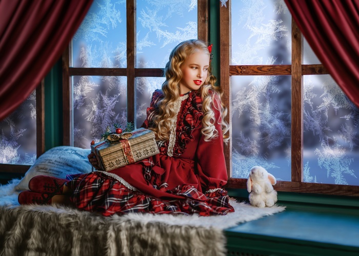 Girl in red dress holding a gift by the window