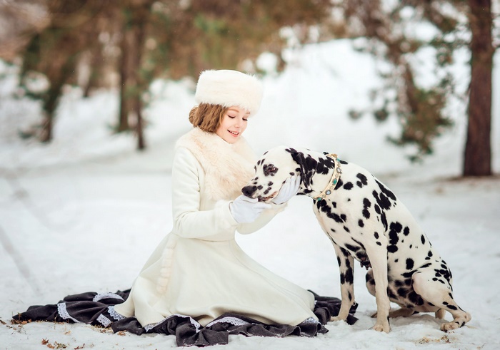 Girl in winter coat with Dalmatian dog
