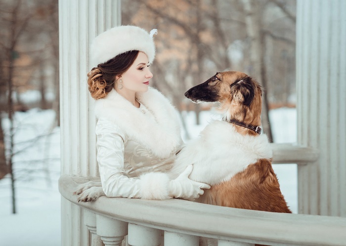 Woman in white fur coat with Borzoi dog in gazebo