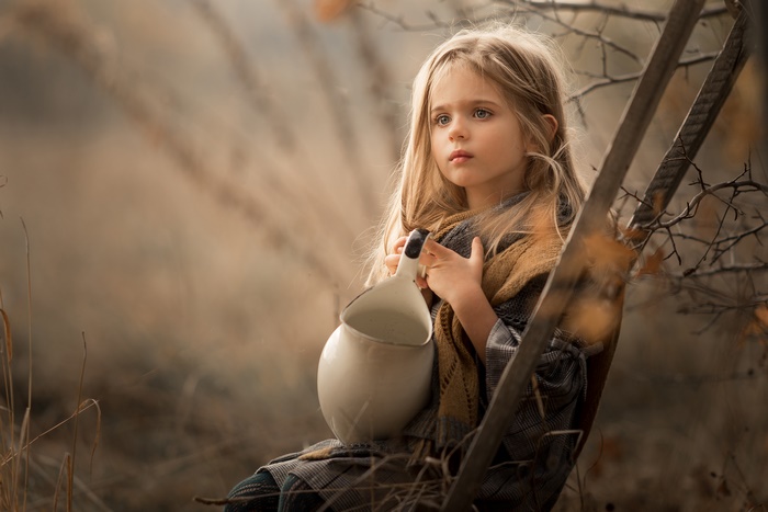 Young blonde girl holding a pitcher outdoors