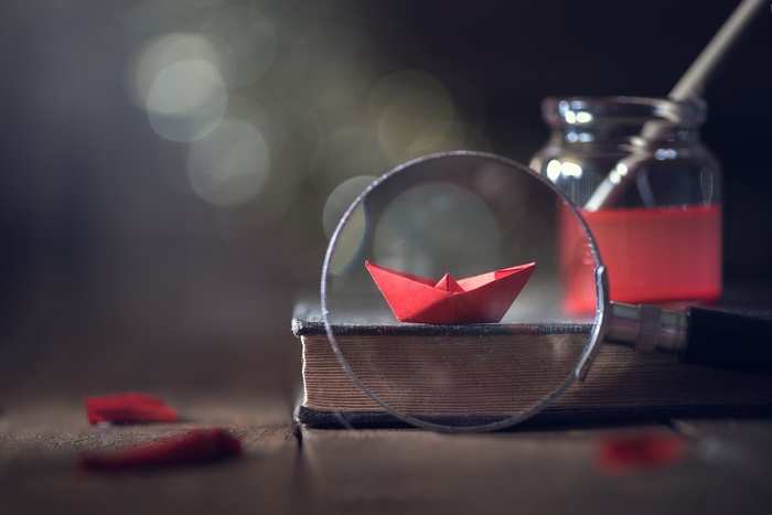Origami paper boat on a book with inkwell