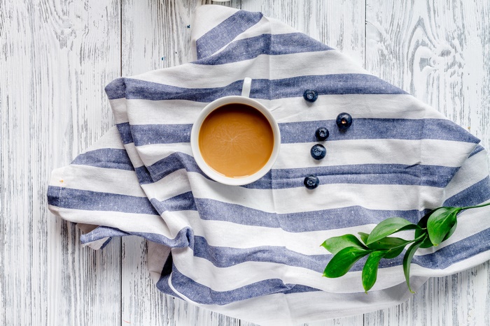 Coffee cup with blueberries on a striped cloth
