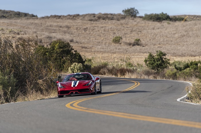 Red Ferrari 458 Speciale driving on a winding road
