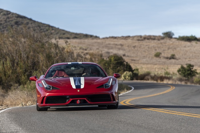 Red Ferrari 458 Speciale driving on a winding road