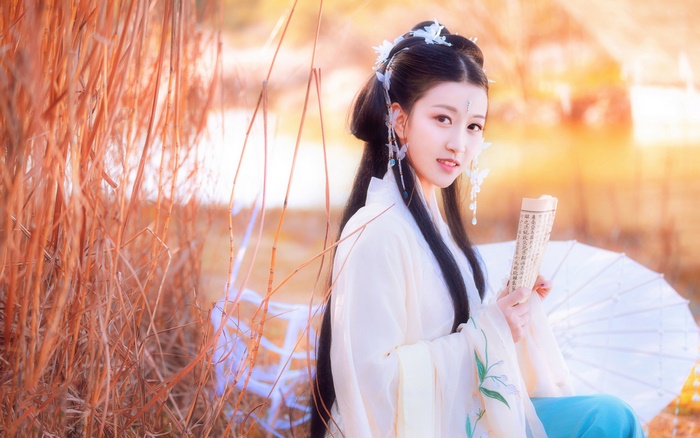 Young woman in traditional Chinese attire holding a scroll