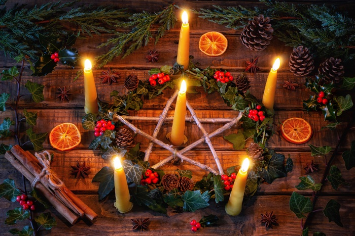 Christmas candles arranged in a pentagram with pine cones and oranges