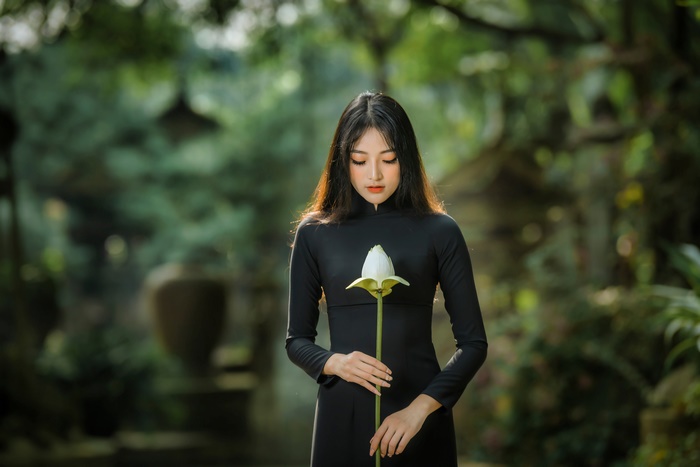Woman in black dress holding a lotus flower