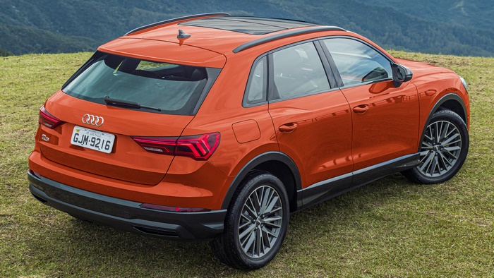 Orange Audi Q3 SUV parked on grassy hill