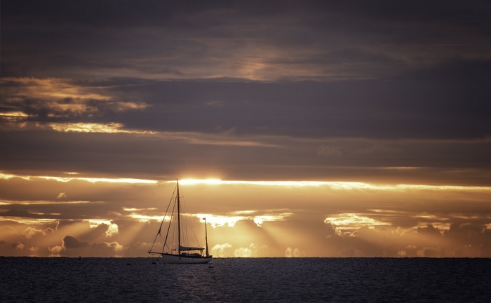 Sailboat on the sea at sunset with dramatic clouds
