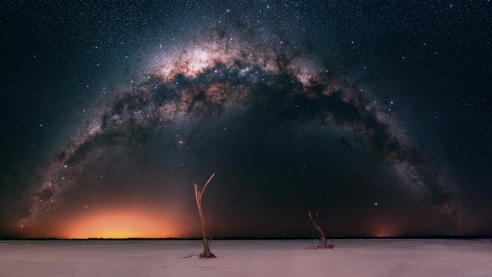 The Milky Way Arching Over A Desert Landscape